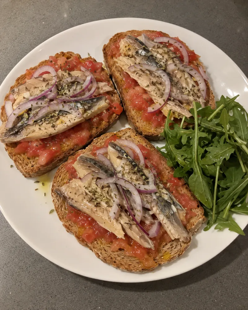 Tostas de pan integral con tomate rallado, filetes de caballa y cebolla morada