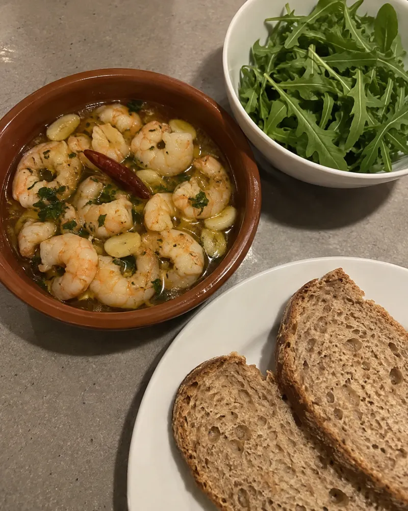 Cazuela de barro con langostinos al ajillo, guindilla y pan integral