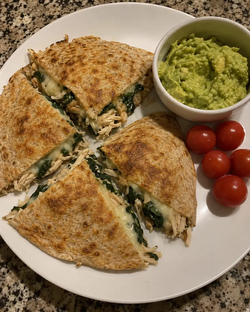 Quesadilla integral dorada en 4 triángulos con pollo, espinacas, mozzarella y guacamole